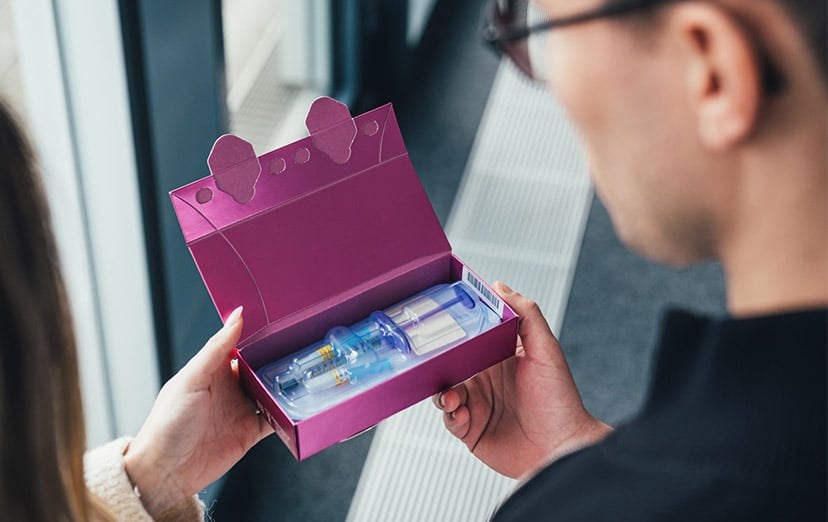 Hand hält eine geöffnete Premiumverpackung mit vorfüllbaren Spritzen für Medical Aesthetics
